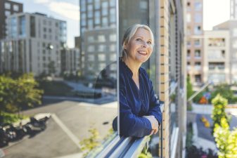 A woman looks out on a balcony in the city