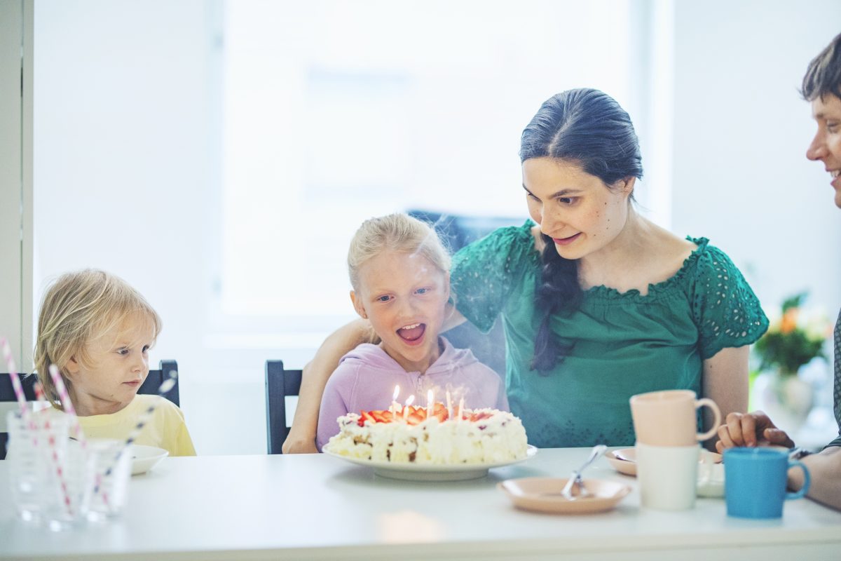 Perhe juhlii tyttären synttäreitä kakun kera.