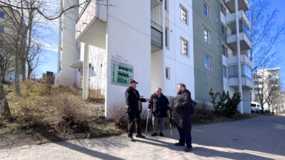 kolme henkilöä keskustelee talon edustalla